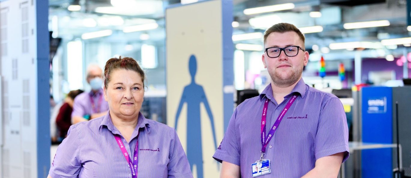 Woman and man standing in front of body scanner