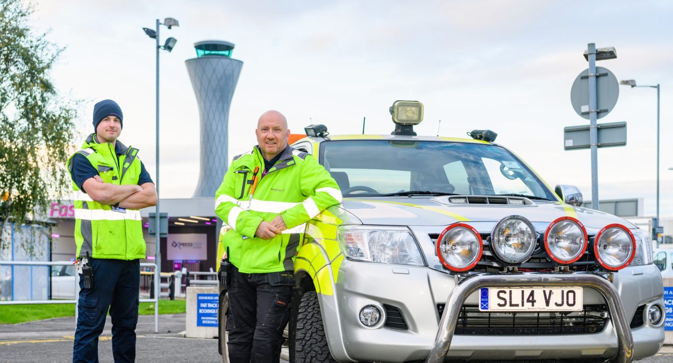 Two men standing next to vehicle