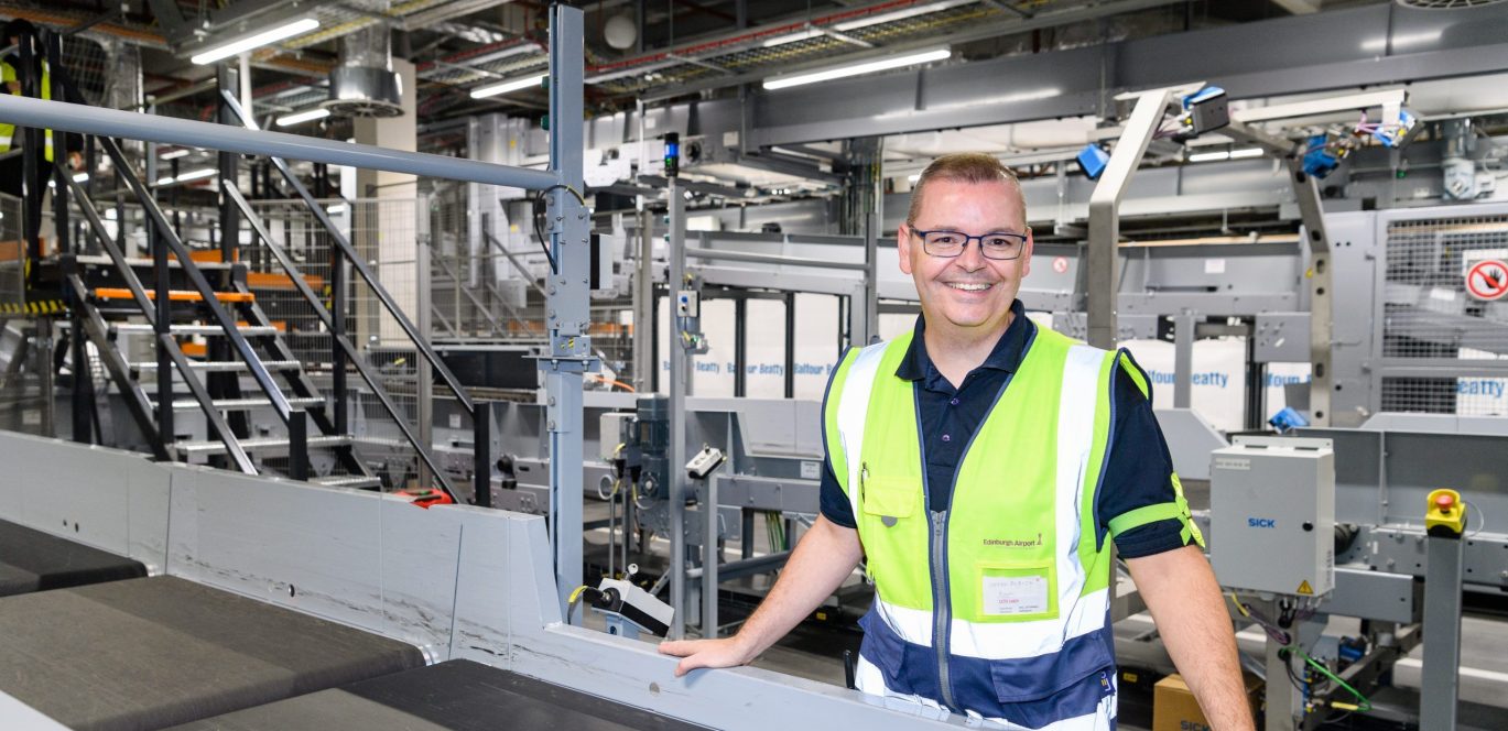 Man standing next to baggage belt