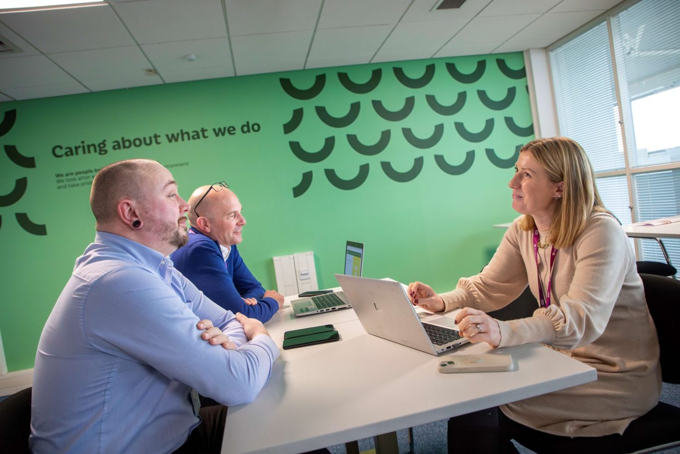 3 members of Legal and Compliance team sat around a desk working